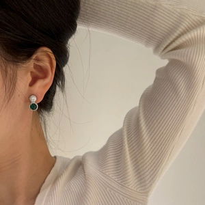 Détail de boucles d'oreilles en argent avec gemmes vertes et diamants sur modèle