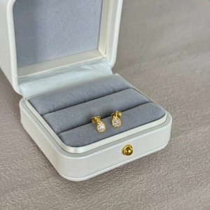 Detailed macro view of gold teardrop earrings with crystals in a luxury gift box