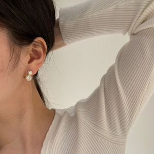 Gros plan de boucles d'oreilles double cercle dorées avec cristaux portées par un mannequin