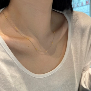 Close-up of S925 sterling silver dual-tone necklace worn on a neck with gold beads