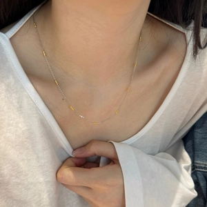 Detail of S925 sterling silver necklace featuring two-tone gold cylinder beads on silver chain