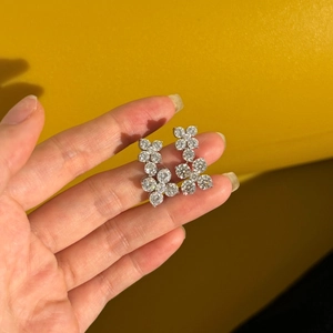 Macro shot of silver four-leaf clover earrings featuring brilliant-cut clear gemstones