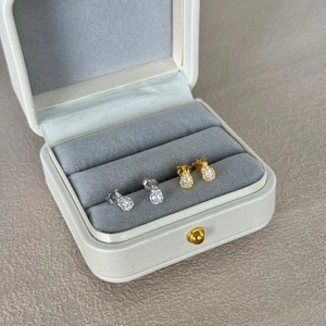 Elegant pear-cut silver and gold stud earrings displayed in a velvet jewelry box