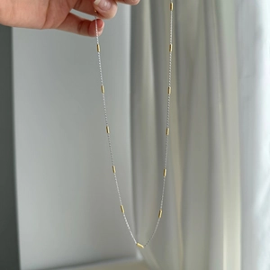 Detailed shot of two-tone S925 sterling silver necklace with gold cylindrical accents