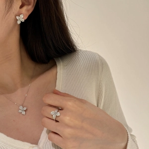 Macro shot of silver floral jewelry set with sparkling pavé stones on a female model