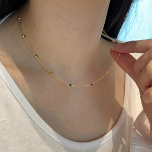 Close-up of a gold s925 silver necklace with colorful beads on a white ribbed fabric background