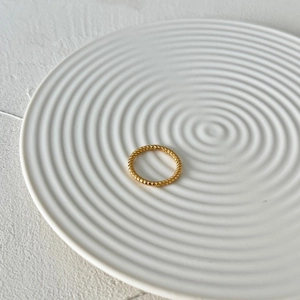 Detail of twisted rope texture golden S925 sterling silver ring on decorative tray