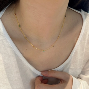 Detailed close-up of a delicate gold necklace featuring colorful beads on a thin chain