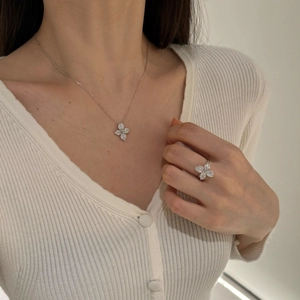 Detail shot of a sparkling silver flower jewelry set with necklace and ring on a model