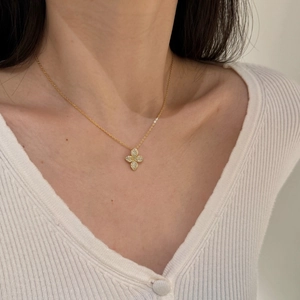 Close-up of a sparkling pavé flower pendant on a delicate gold necklace worn by a model