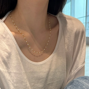 Detail of elegant S925 silver gold chain with delicate white beads on female collarbone