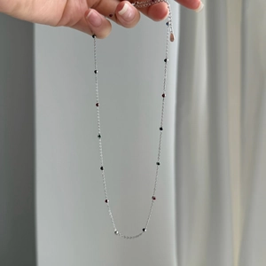 Close-up of S925 silver necklace with red, green, and black zircon beads and lobster clasp