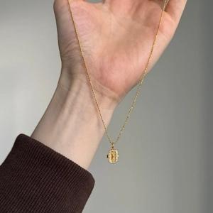 Gros plan d'un collier pendentif doré vintage avec pierre rouge et détails en zircon blanc