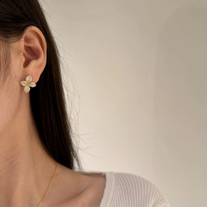Detailed view of flower earrings in gold finish with sparkling cubic zirconia pavé