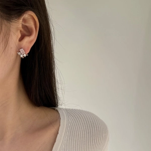 Macro detail of butterfly stud earrings featuring pink and white gemstones on ear lobe