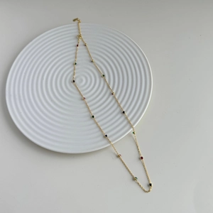 Close-up of golden S925 silver necklace with colorful round beads and heart charm pendant