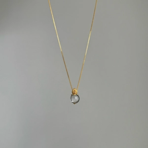 Detail of S925 silver necklace with white crystal pendant and golden floral cap