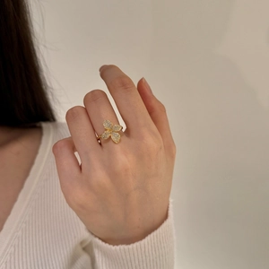 Close-up of a gold butterfly ring with micro-pave crystals on a model's finger