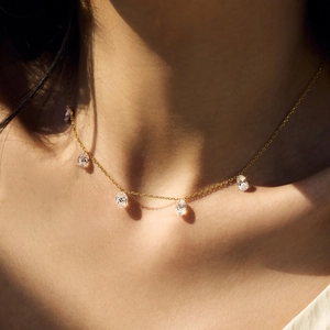 Close-up of golden necklace with five oval-cut sparkling zircon stones on female neck