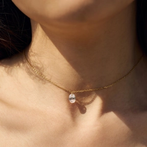 Detailed view of an oval zircon pendant on a gold S925 silver chain worn by a model