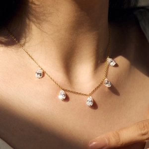 Elegant gold necklace with five pear-cut clear crystal teardrops worn by a model