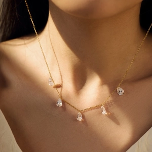 Close-up of gold S925 silver necklace with five teardrop zirconia charms on model neck