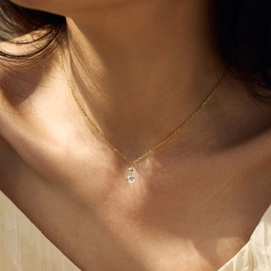 Detail of elegant gold gourd necklace with crystals worn by model in natural light