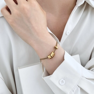 Dettaglio del bracciale in argento S925 con perline nere e monete d'oro al polso