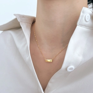 Dettaglio della collana a barra dorata minimalista da donna con zircone a stella