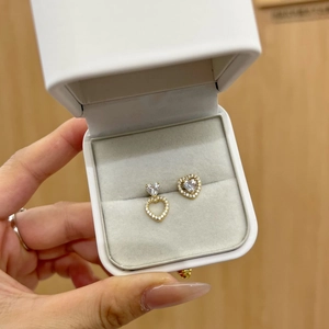 Asymmetric gold heart earrings with white cubic zirconia in a jewelry gift box