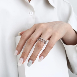 Detail of silver S925 wave ring with dangling polished metal beads on a model finger