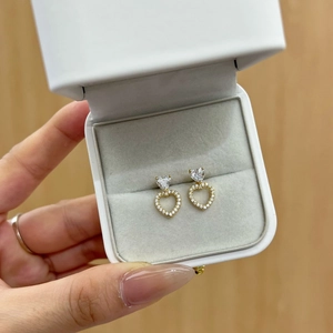 Macro detail of heart-shaped gold earrings with crystals in a premium gift box