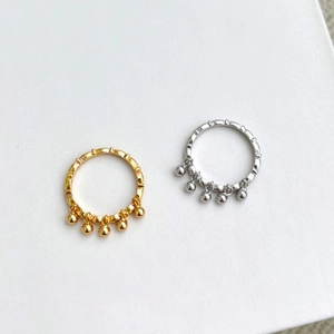 Detailed macro view of S925 silver wave rings with gold and silver bead fringe charms