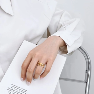 Vue détaillée d'une bague feuille dorée avec zircons blancs sur le doigt d'un mannequin