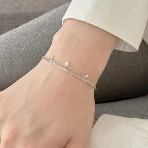 Détail macro d'un bracelet à double chaîne en argent 925 avec petits pendentifs clairs