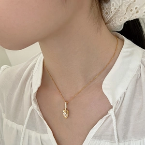 Close-up of a delicate gold shovel pendant set with sparkling zircons on a model