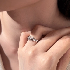Close-up of interlocking S925 silver rings with pavé diamonds on a model finger