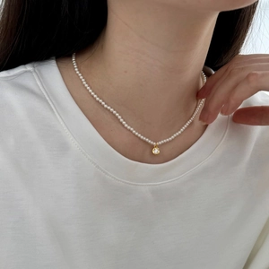 Macro view of dainty pearl choker with a sparkling gold cubic zirconia pendant