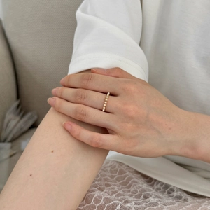 Close-up of minimalist gold ring featuring a row of seven small white pearls for women