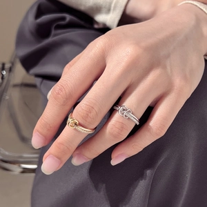 Close-up of interlocking silver and gold rings featuring pavé zircon stones on a hand
