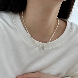 Detail of S925 silver necklace with delicate pearls and round pendant on a model