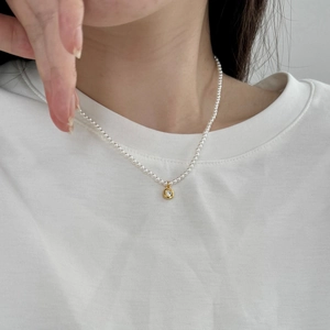 Detail of S925 silver necklace featuring white pearls and a gold pendant with a clear stone