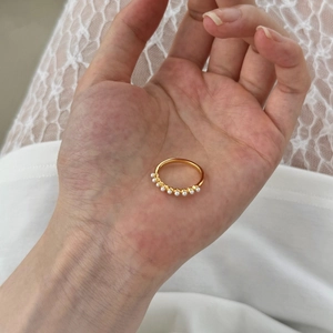 Close-up of gold S925 silver ring with small white pearls on white lace background