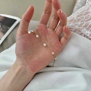 Elegantes goldenes S925 Silberarmband mit weißen Perlen und einem glitzernden Kleeblatt