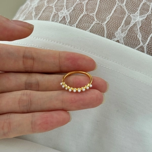 Detail view of dainty gold S925 silver ring with small white pearls in a row