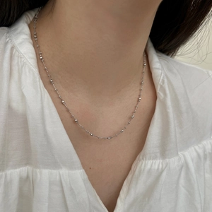 Élégant collier à perles minimaliste en argent S925 porté sur une chemise blanche