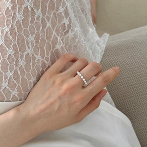 Close-up of S925 silver ring featuring elegant row-set pearls on finger with lace