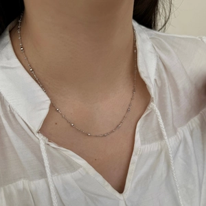 Gros plan d'une chaîne en argent sterling S925 avec petites perles portée sur le cou