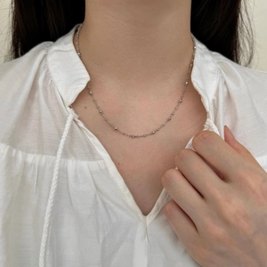 Détail du collier à perles en argent S925 porté sur un col de chemise blanche chic