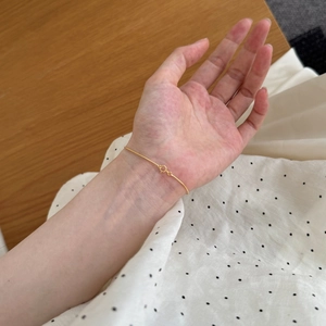 Close-up of minimalist gold thin snake chain bracelet worn on wrist with spring clasp